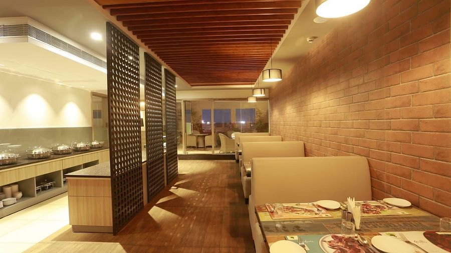 MInt N Musttard Restaurant at Mayberry Tiruppur with sofa chairs and tables arranged with table mat and cutleries